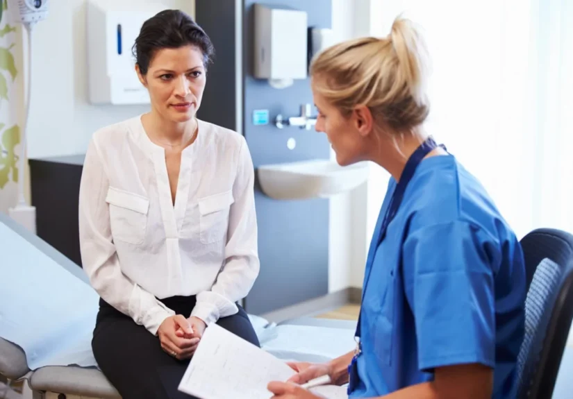 Female Patient And Doctor Have Consultation In Hospital Room